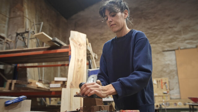 Woman carpenter planing wood block. Feminist girl process timber bar. Male carpentry work. Female joiner made woodwork. Feminism worker. Person create art project. Diy master class workshop. Hand job.