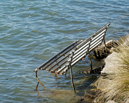 Park bench swamped by a rising sea level, New Zealand.