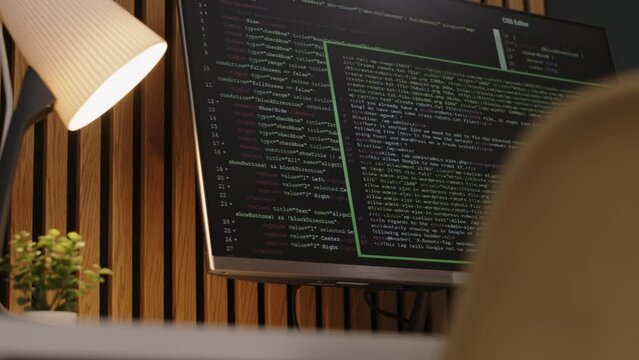 No people shot of programming code script on black desktop computer screen at table in modern office