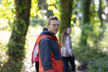 Man in Red and Black Jacket Walking Through Forest