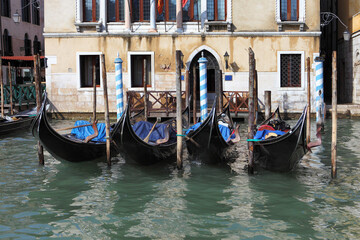 Several gondolas are moored in the canals of Venice, surrounded by picturesque medieval buildings.