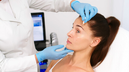 Close-up. Before the procedure for facial contouring or plastic surgery, the cosmetologist makes markings on the patient’s face. Time to prepare for a cosmetic procedure.