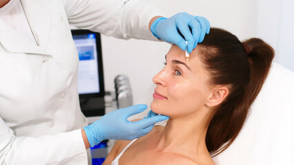 Close-up. Before the procedure for facial contouring or plastic surgery, the cosmetologist makes markings on the patient’s face. Time to prepare for a cosmetic procedure.