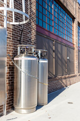 Two large tanks are chained to a brick wall