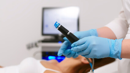 A cosmetologist performs vacuum cleaning and polishing of the facial skin of a middle-aged woman in a cosmetology clinic. Professional moisturizing and rejuvenating hardware procedures.