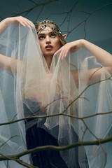 A young woman, dressed as an elf princess, adorns a flowing veil on her head in a studio setting.