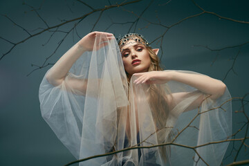 A young woman, dressed as an elf princess, stands with a veil adorning her head in a mystical studio setting.
