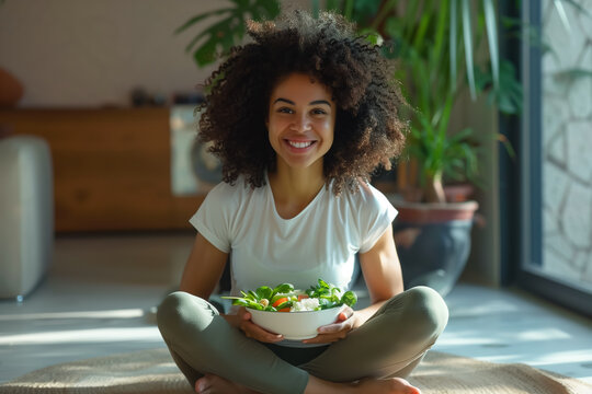 Beautiful fit woman eating healthy salad after fitness workout, Young woman enjoys a fresh salad, embodying a picture of health and happiness in her bright home.