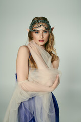 A young woman adorned in a veil and headpiece, embodying a fairy fantasy with an enchanting studio setting.