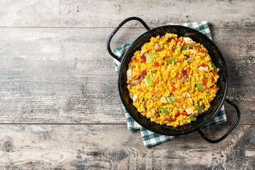 Yellow rice with chicken and vegetables on wooden table. Top view. Copy space