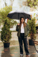 Rainy day asian woman wearing a raincoat outdoors. She is happy.She used her hand to touch the rain.