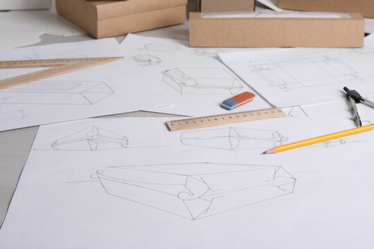 Creating packaging design. Drawings, boxes and stationery on light table, closeup