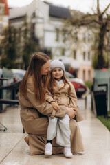 young happy mother hugs her daughter in the city