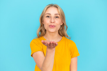Woman sending air kiss with open palm on blue background