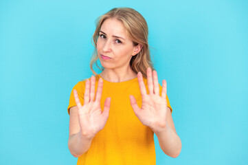 Woman showing stop gesture by hands on blue background