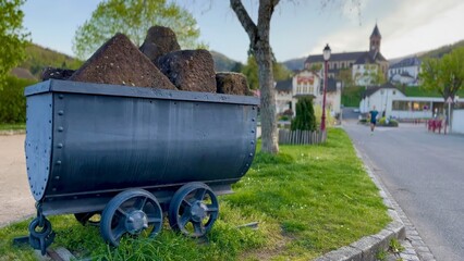 Vibrant Village Life in Buhl with Historic Sandstone Quarry Cart, Alsace, France, with Running Man in Background - obrazy, fototapety, plakaty