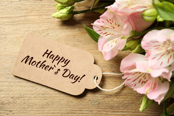 Happy Mother's Day greeting label and beautiful flowers on wooden table