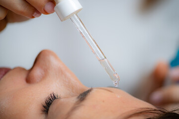 Professional cosmetician applying hyaluronic acid serum for a radiant, hydrated complexion - 782998062