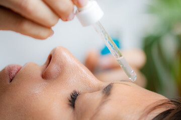 Professional cosmetician applying hyaluronic acid serum for a radiant, hydrated complexion - 782998097