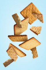 Tasty dry crackers falling on light blue background - obrazy, fototapety, plakaty