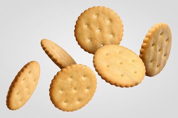 Tasty dry round crackers falling on light grey background