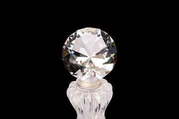Close-up of a brilliant cut diamond on a black background. The faceted gemstones reflect light and...
