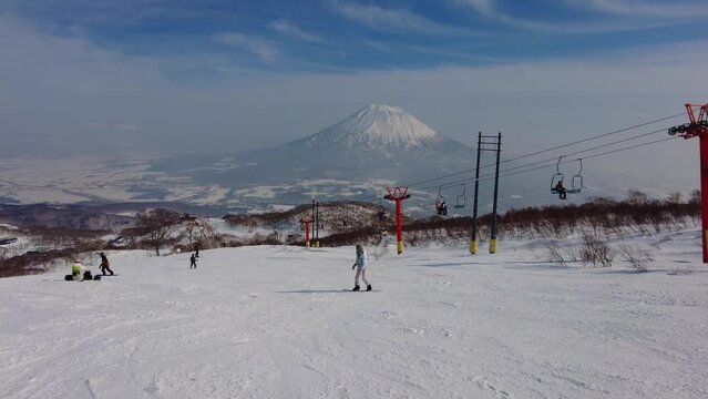 Niseko, Japan: Point of view of a snowboarder riding the slope in the famous Niseko ski resort in Hokkaido with Mt Yotei in the backround on a sunny winter day in northern Japan