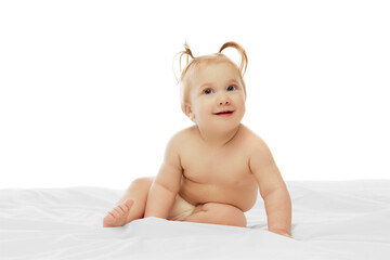 Happy little baby girl, toddler, child in diaper, with ponytails sitting and cheerfully smiling isolated on white background. Concept of childhood, care, health, well-being, parenthood