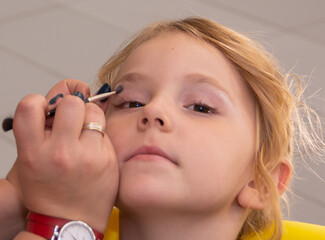 A makeup artist makes makeup for a child 