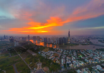 Aerial view of Asia city at sunset by drone with Landmark 81 skycraper modern building, boat on Saigon river, night skyline of Vietnam