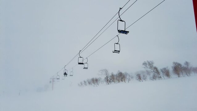Niseko, Japan: Skiers and snowboarder riding the powder snow under a chairlift in the famous Niseko ski resort in Hokkaido in winter in northern Japan