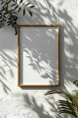 Aesthetic showcase of blank frame on white wall with leaf shadows, exuding tranquility and artistry.