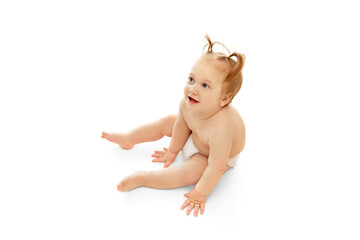 Happy little child, baby girl with two ponytails sitting in diaper isolated on white background. Happy smiling kid. Concept of childhood, care, health, well-being, parenthood