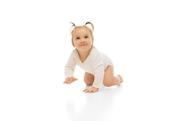 Happy, smiling little baby girl, child with two ponytails crawling isolated on white studio background. Playing and having fun . Concept of childhood, care, health, well-being, parenthood