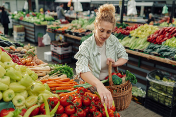 Customer with wicker basket full of produce buying fresh veggies at market