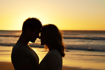 Couple, love and kiss at ocean with silhouette for date or summer holiday and bonding in Florida....