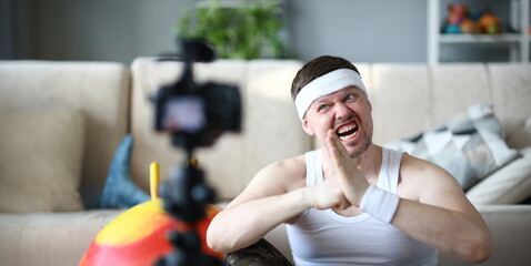 Blogger with Funny Face Record Fitness Exercise. Man Sportsman Shooting Workout on Digital Camera...