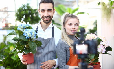 Man and Woman Recording Flower Vlog to Camera. Florists Vlogger Showing Blooming Blue and White Hydrangea in Flowerpot on Camcorder. People with Domestic Plant with Green Leaf in Pot Front View Shot