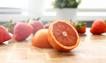 Red orange and strawberry on kitchen table closeup
