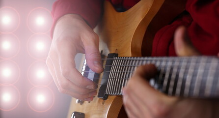 Male arms holding and playing classic shape wooden electric guitar closeup. Six stringed learning...