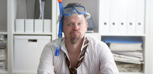 Man wearing suit and tie in goggles with snorkel sit at office workplace ready to take off...