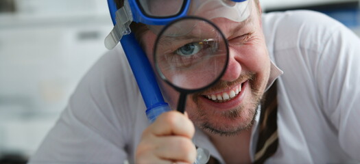 Funny smiling man wearing suit and tie in goggles and snorkel hold in arm magnifier glass at workplace in office portrait closeup. Searching data at online web about tourism 404 page error