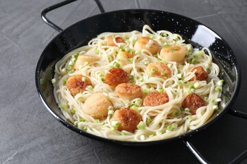 Delicious scallop pasta with green onion on grey table, closeup