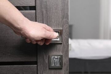 Man opening wooden door indoors, closeup of hand on handle