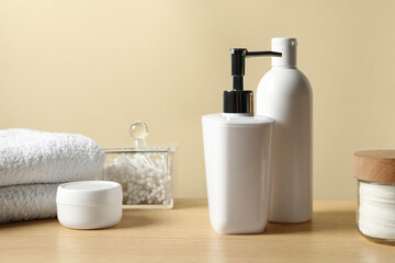 Fototapeta na wymiar Different bath accessories on wooden table against beige background, closeup