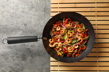Shrimp stir fry with vegetables in wok on grey table, top view