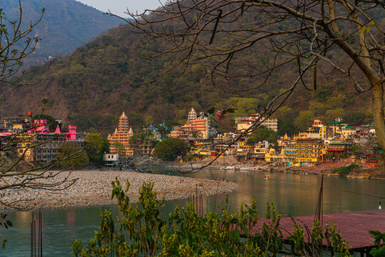 View of River Ganga and Laxman Jhula bridge at sunset with a blue sky and colourful houses. Rishikesh. India.