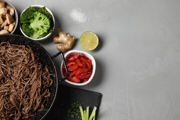 Wok with noodles, chicken and other products on light grey table, flat lay. Space for text