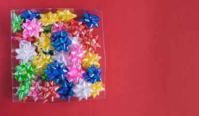 Transparent box full of colorful decorations on red background. Copy space.