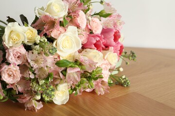 Beautiful bouquet of fresh flowers on wooden table near white wall, closeup. Space for text